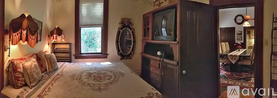 A bedroom with a large bed and a wooden cabinet.