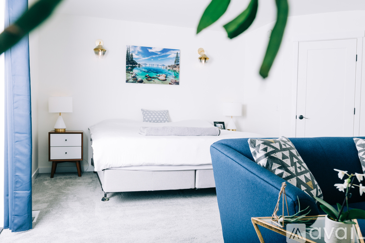 A bedroom with a white bed and a blue chair.