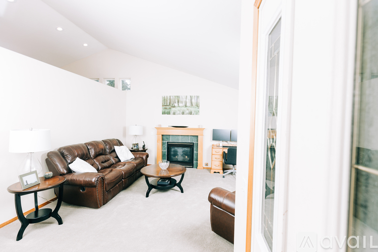 A living room with a brown leather couch and a fireplace.