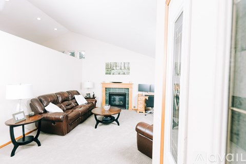 A living room with a brown leather couch and a fireplace.