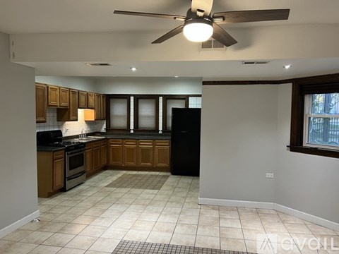 A kitchen with a black refrigerator, black countertops, and brown cabinets.