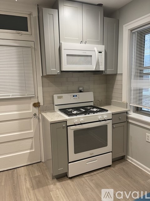 A white kitchen with a stove top oven and microwave above it.