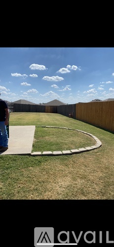 A person is standing on a concrete path in a grassy area.