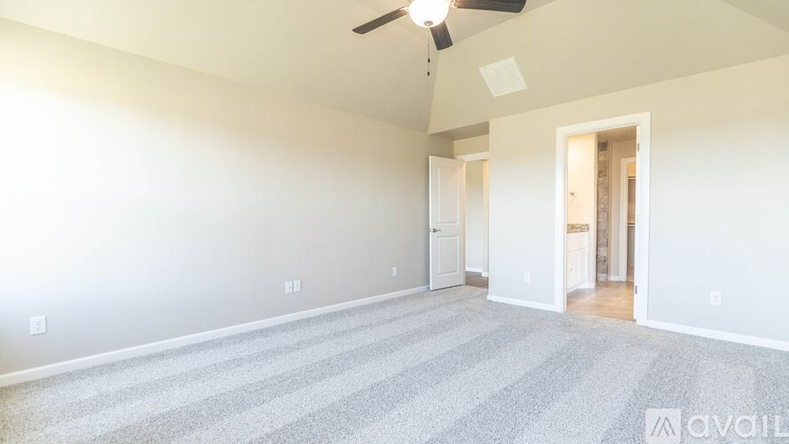 A spacious room with a carpeted floor and a ceiling fan.