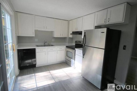 A kitchen with white cabinets and a stainless steel refrigerator.