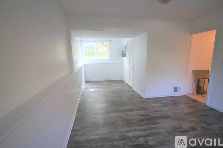 A spacious room with a window and a door leading to another room.