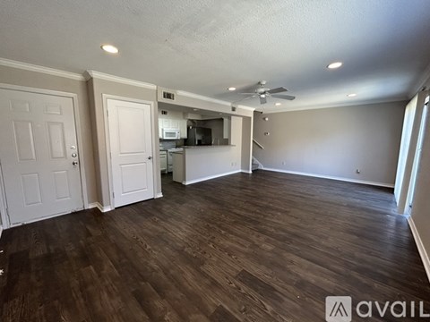 A spacious room with wood flooring and a ceiling fan.