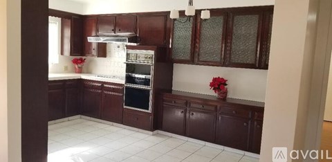 A kitchen with brown cabinets and a white tile floor.