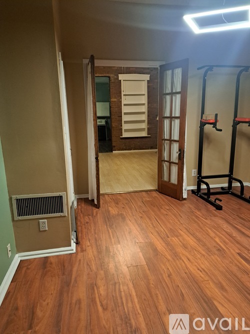 A room with wooden floors and a gym equipment set up.