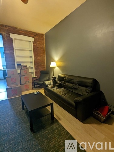 A living room with a black leather couch and a coffee table.