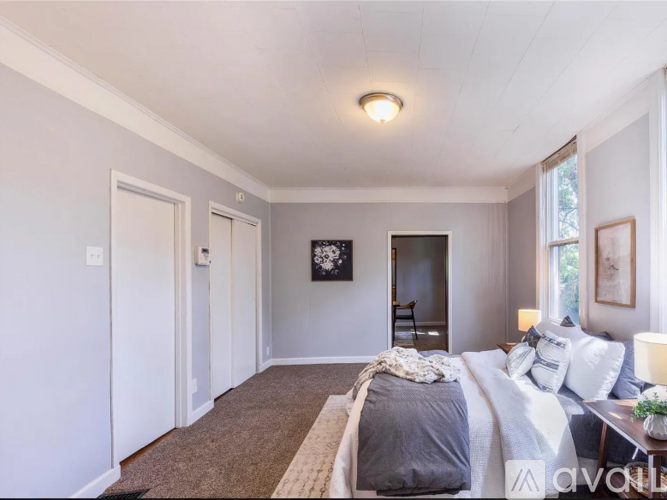 A bedroom with a bed, a chair, and a painting on the wall.