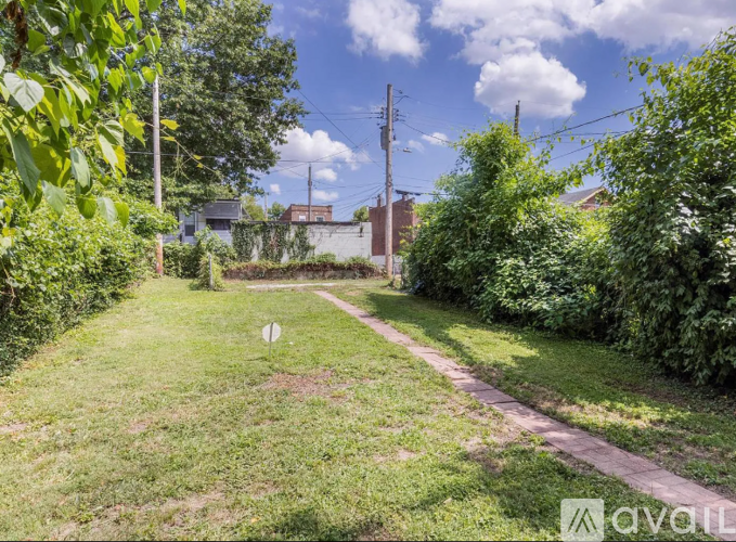 A grassy area with a path and a white sign in the distance.