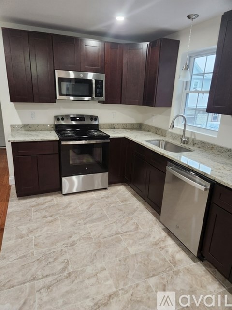 A kitchen with dark brown cabinets and a stainless steel dishwasher.