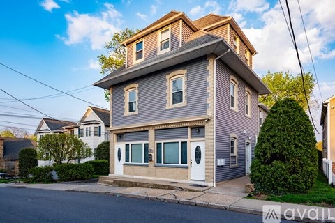 A two-story house with a grey exterior and a white door is for sale.