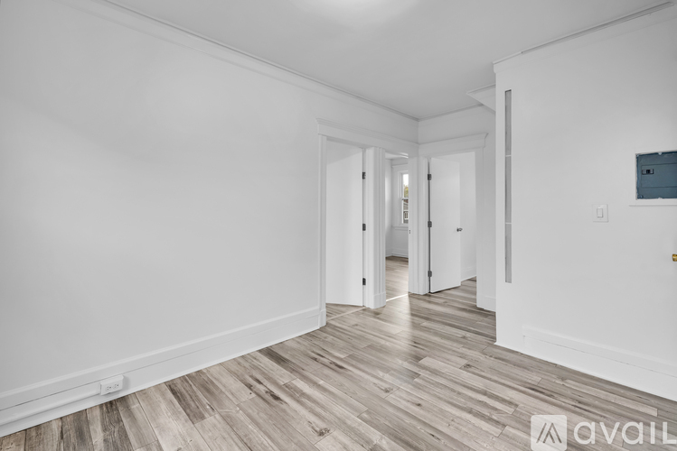 A spacious room with wooden flooring and white walls.