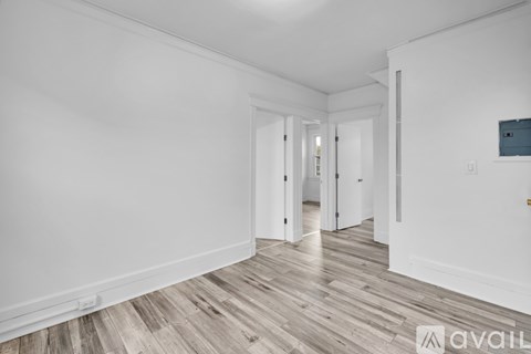 A spacious room with wooden flooring and white walls.