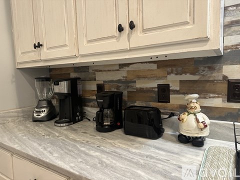 A kitchen counter with a blender, two coffee makers, and a toy chef.
