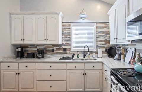 A kitchen with white cabinets and a stone backsplash.