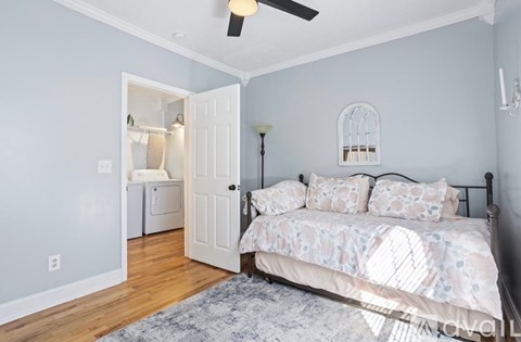 A bedroom with a bed, a ceiling fan, and a doorway leading to another room.