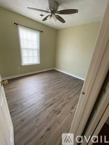 A room with a ceiling fan and a window with blinds.