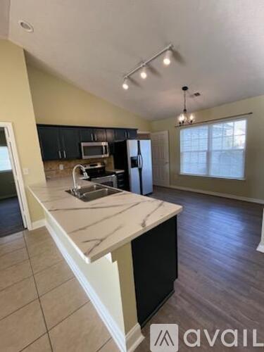 A kitchen with a marble countertop and black cabinets.