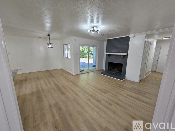 A spacious room with wooden flooring and a fireplace.