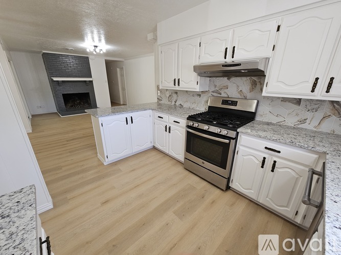 A kitchen with white cabinets and a wooden floor.