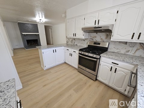A kitchen with white cabinets and a wooden floor.