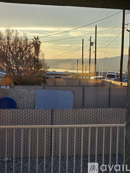 A fence with a sign that reads "AVAIL" in front of a building and a tree.
