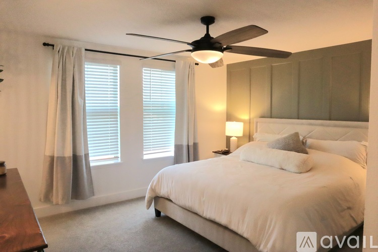A bedroom with a large bed and a ceiling fan.