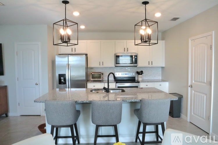 A kitchen with a granite countertop and bar stools.