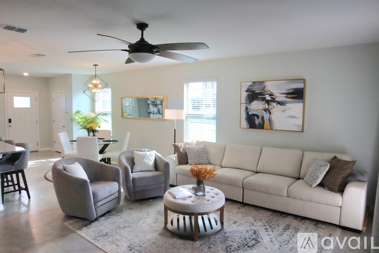 A living room with a white couch, grey armchairs, and a coffee table.