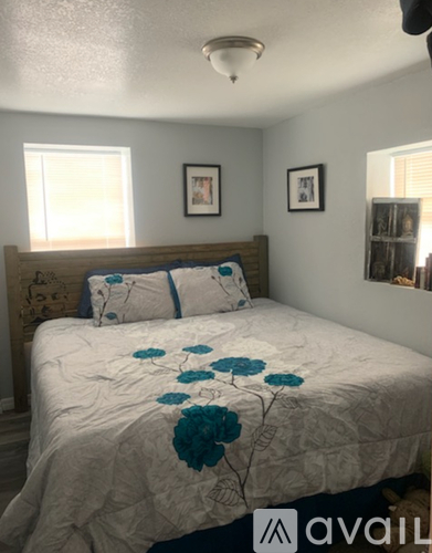 A bedroom with a bed in the center and two pictures on the wall.