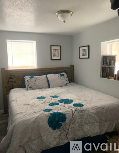 A bedroom with a bed in the center and two pictures on the wall.
