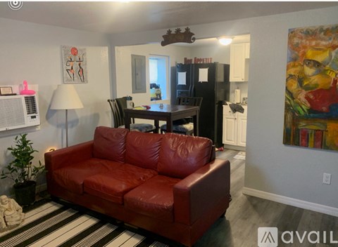A living room with a red couch and a painting on the wall.