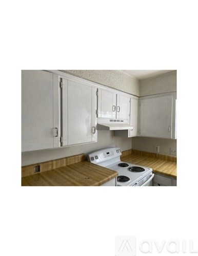 A kitchen with white cabinets and a white stove top oven.