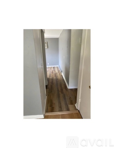 A hallway with wooden floors and white walls.