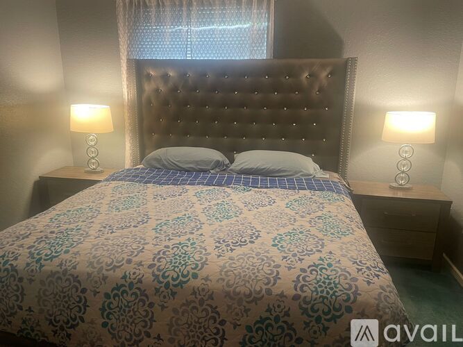 A bed with a patterned cover and a dark headboard is in the image.