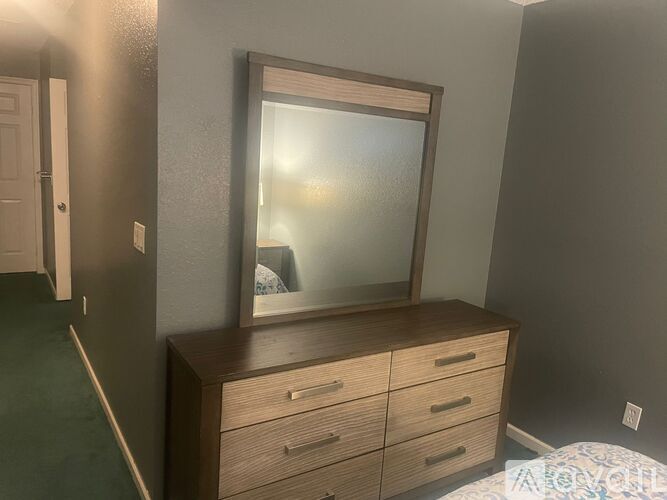 A large mirror is on top of a wooden dresser with six drawers.
