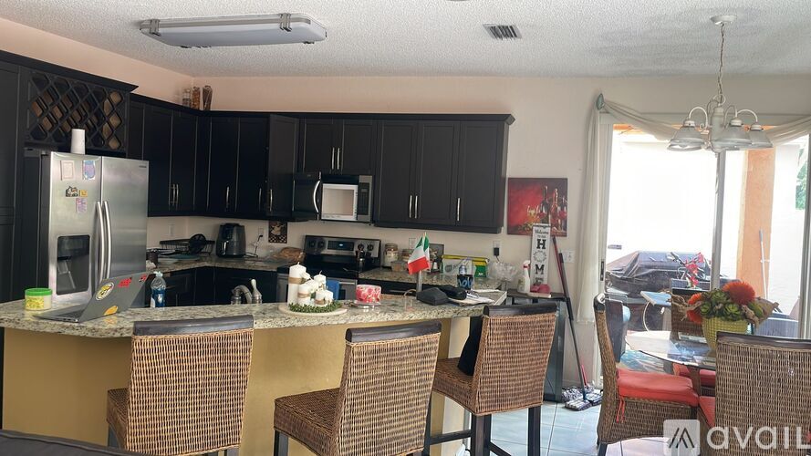 A kitchen with black cabinets and a table with chairs.