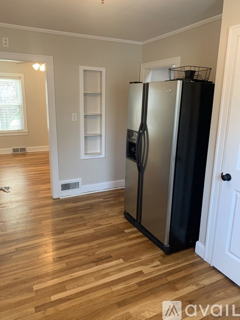 A black refrigerator in a kitchen with wood flooring.