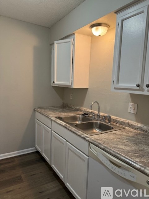 A kitchen with white cabinets and a granite countertop.