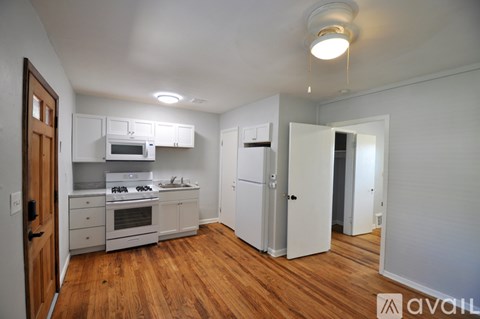 A kitchen with white appliances and wooden floors.