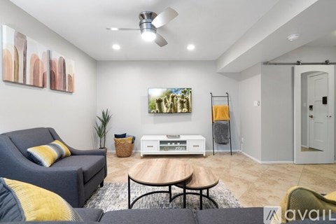 A living room with a grey couch, a coffee table, and a painting on the wall.