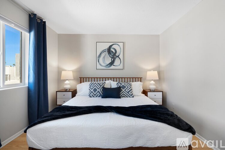 A bedroom with a large bed and a window with blue curtains.