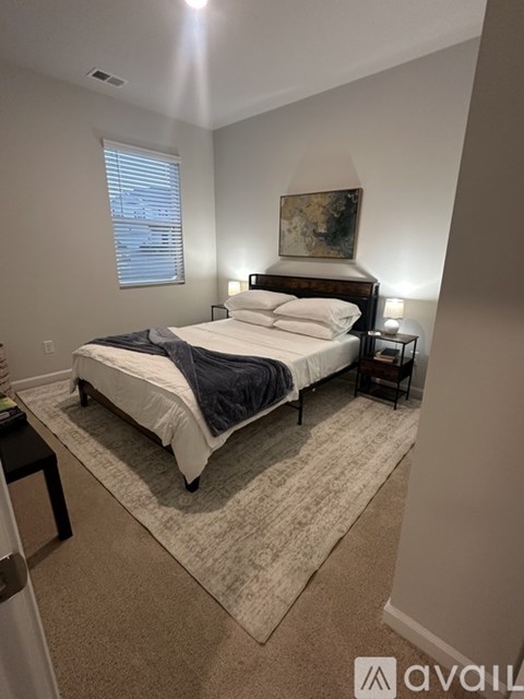 A bedroom with a bed, nightstands, and a painting on the wall.