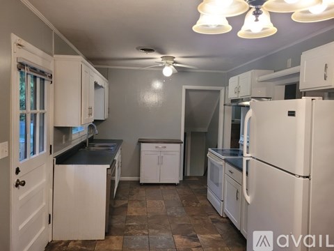 A kitchen with white cabinets and a refrigerator.
