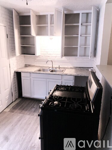A kitchen with a black stove top oven and white cabinets.