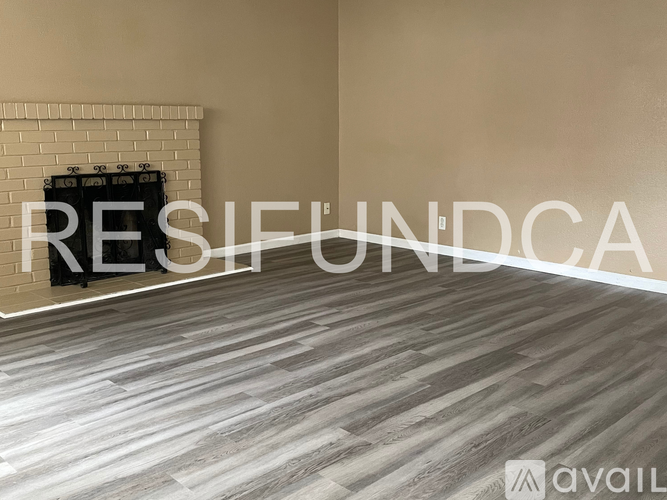 A room with a brick fireplace and a wooden floor.