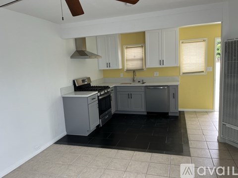 A kitchen with white cabinets and a black floor.
